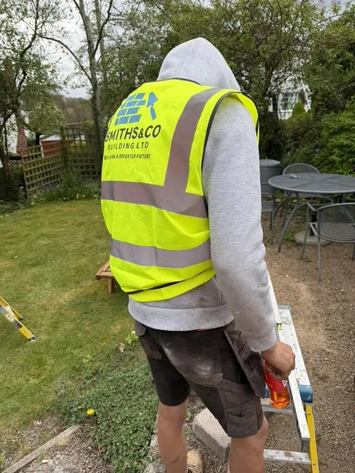 A Smiths & Co team member in branded hi-vis, viewed from behind, on a domestic garden job