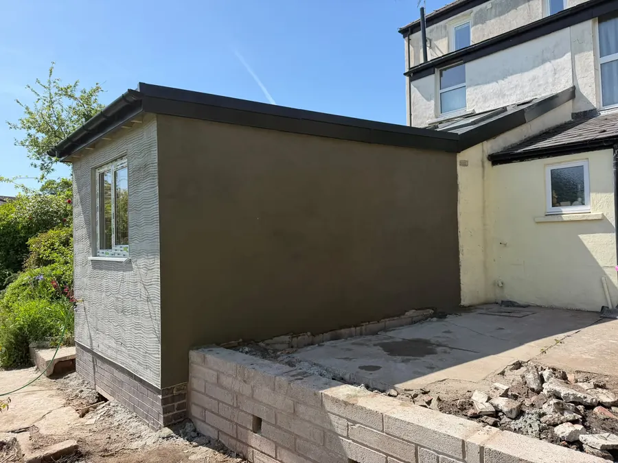 A finished flat-roof extension, rendered and painted, with a blockwork retaining wall alongside