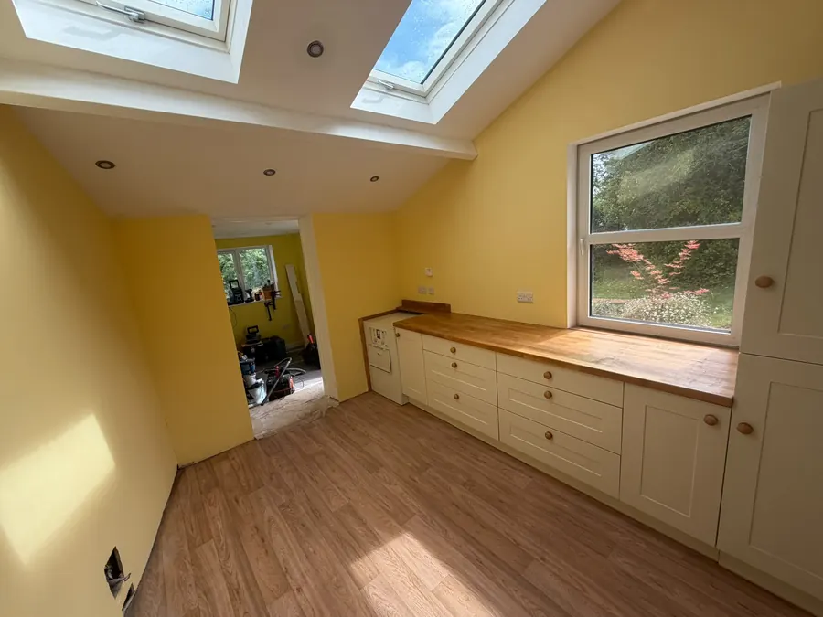 A finished extension interior with fitted bench seating, a timber worktop and roof lights