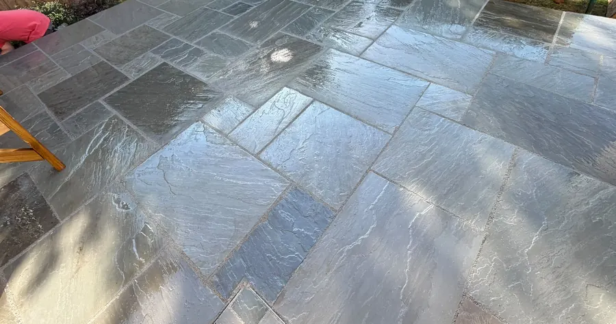 Large-format Indian sandstone paving laid and pointed across a garden patio