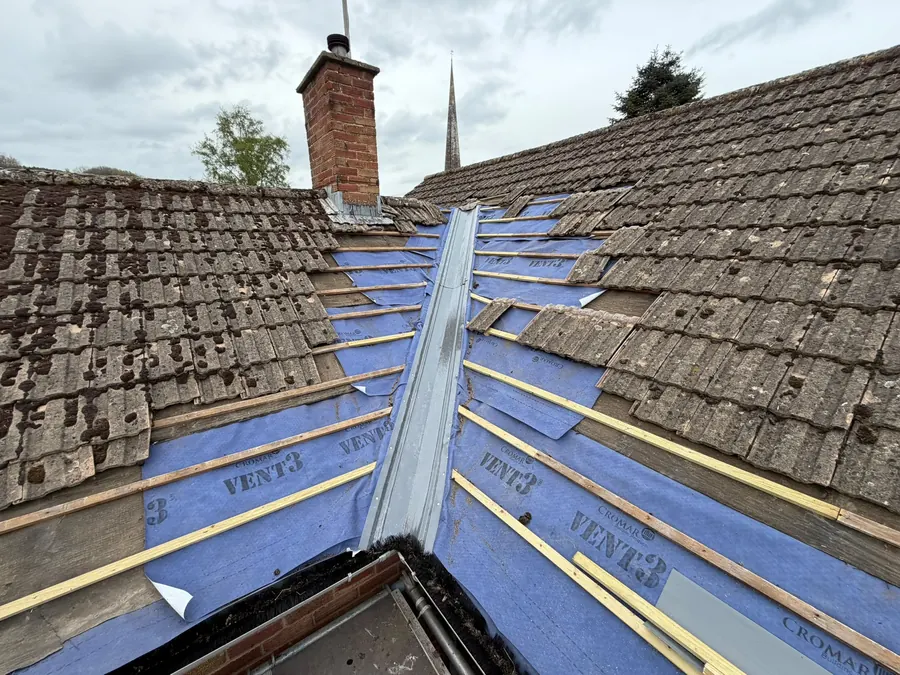 A new roof valley with breather membrane and battens fitted, old tiles either side